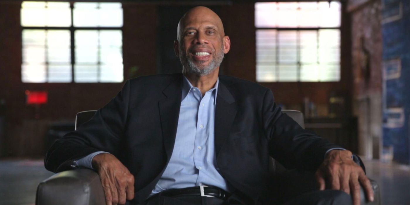 Kareem sitting on a couch and wearing a suit in Minority of One